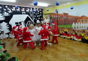 Dzieci na tle zimowej dekoracji wykonują w parach układ taneczny.